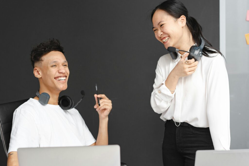 Two cheerful call center agents talking and laughing during a work break.